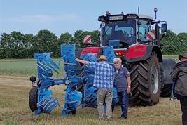 Zwei Maenner vor einem Traktor mit Pflug auf der VErsuchsstation in Dedelow