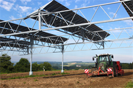 Traktor bei der Aussaat unter einer Agri-PV-Anlage. 